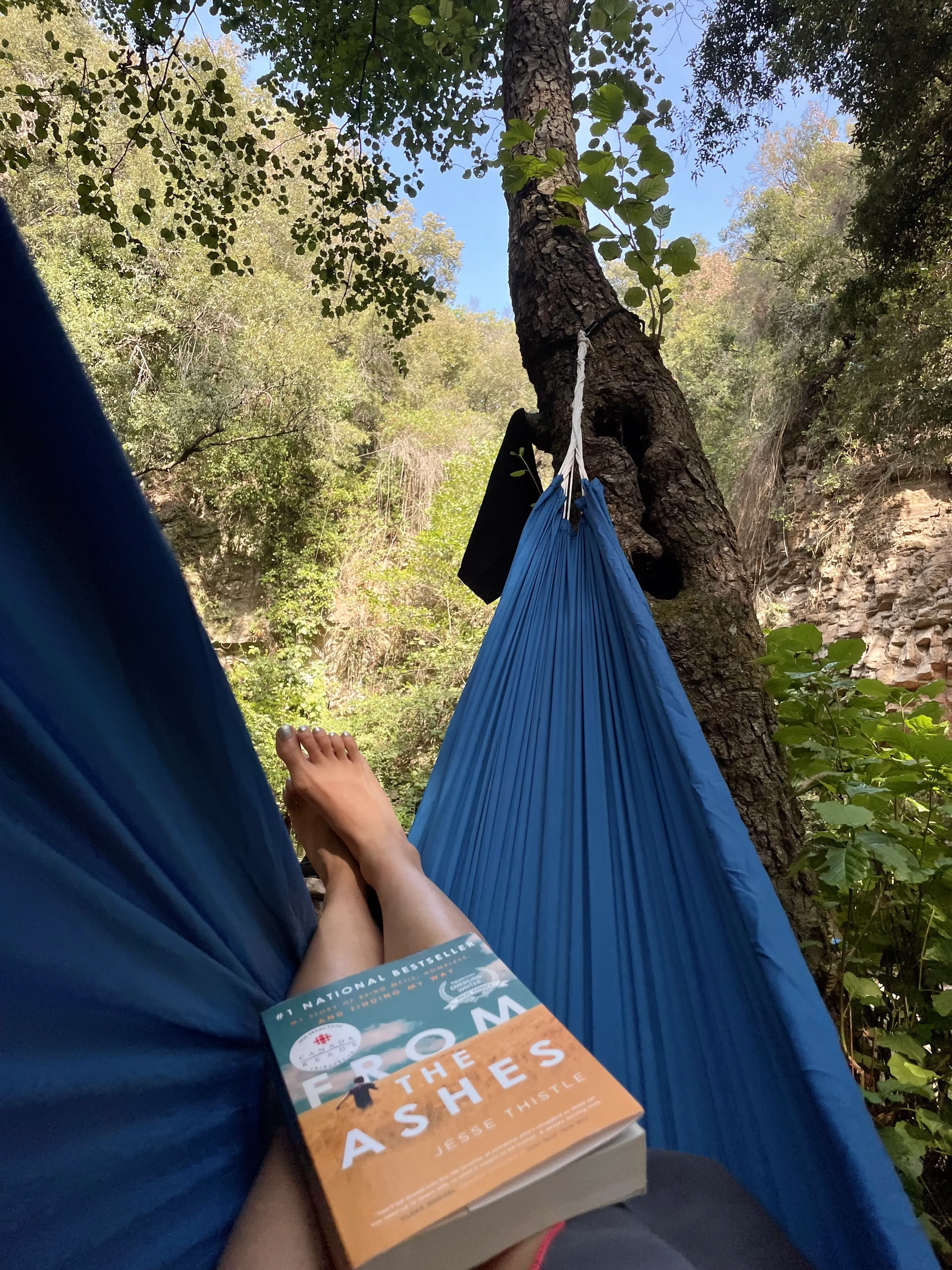 Me lying in a hammock with a book in my lap.