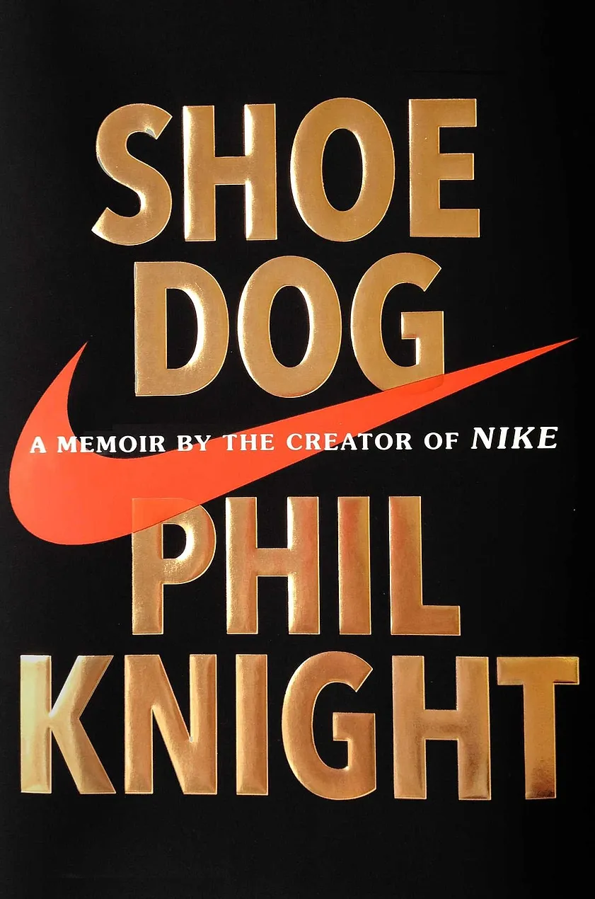 Book title and author's name in large golden font on a black background and Nike's logo placed in the middle covering the width of the book.